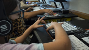 Children's hands on audio production equipment during beat-making class