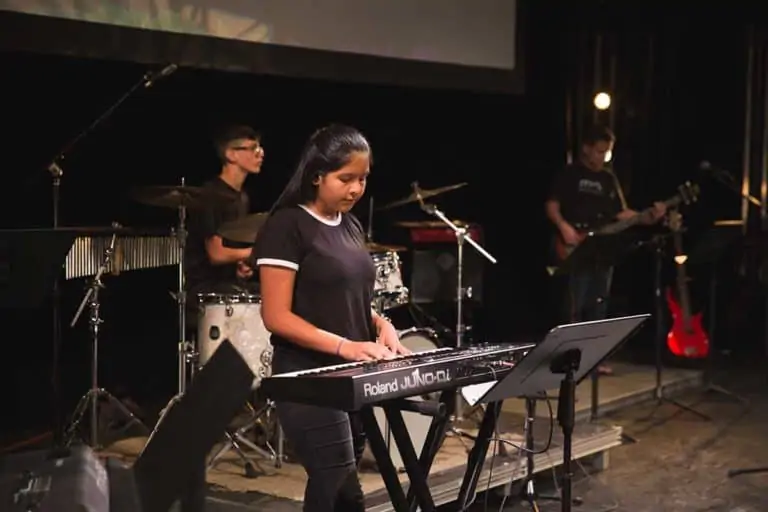 PCM Students playing drums and keyboard on stage.