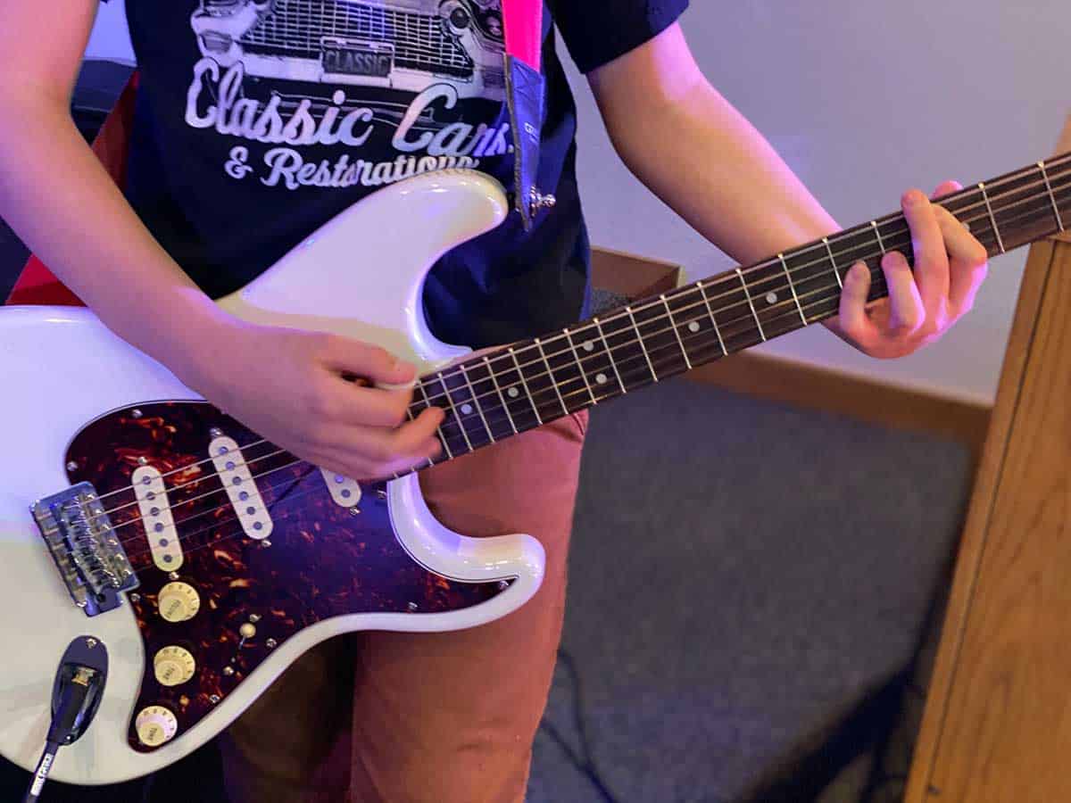 Close up of young guitar player, playing a white guitar.