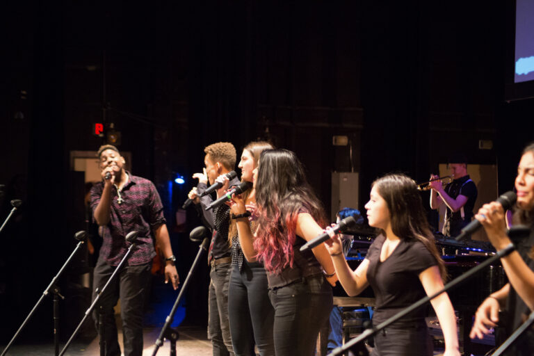 Six Phoenix Conservatory of Music students in their teens, singing on stage during a performing.
