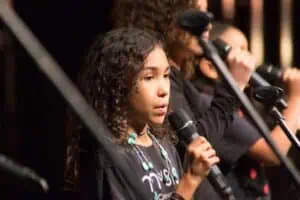 Phoenix Conservatory of Music young singer, holding a microphone and singing on stage.