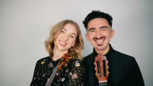 Meghan Ruel & Diego Miranda posing with a violin and guitar, respectively.