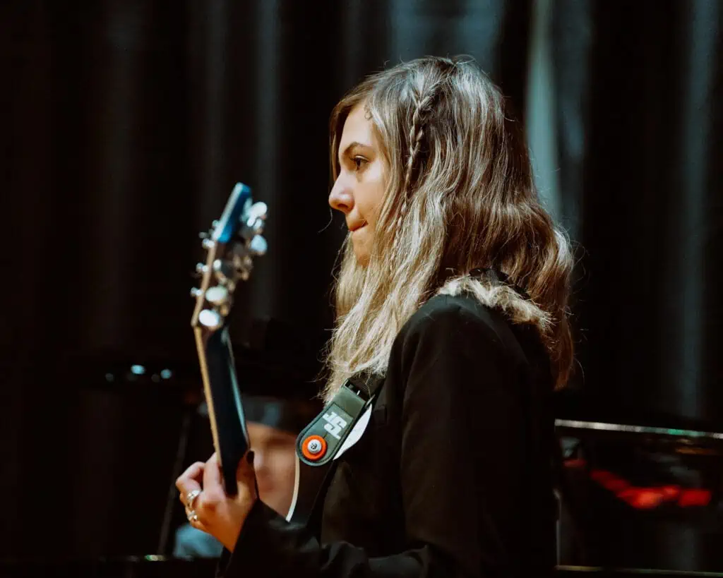 Teenager holding guitar standing on stage.